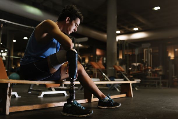 Male athlete with a disability sitting in gym, uncertain