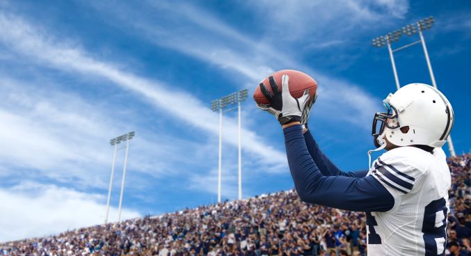 Professional football player making a catch in front of a stadium full of spectators