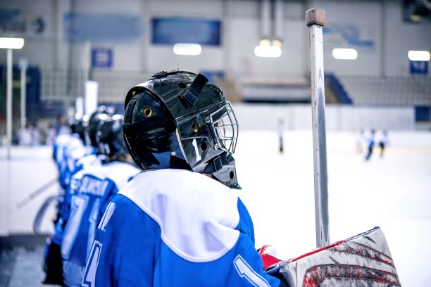 Youth hockey player sitting on bench in blue jersey