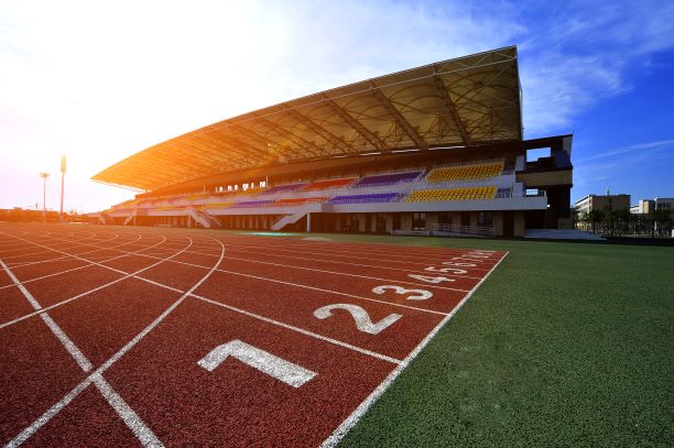 An outdoor track with colourful bleachers in the background.