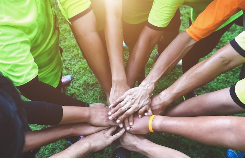 A team gathered with hands in middle getting ready to cheer