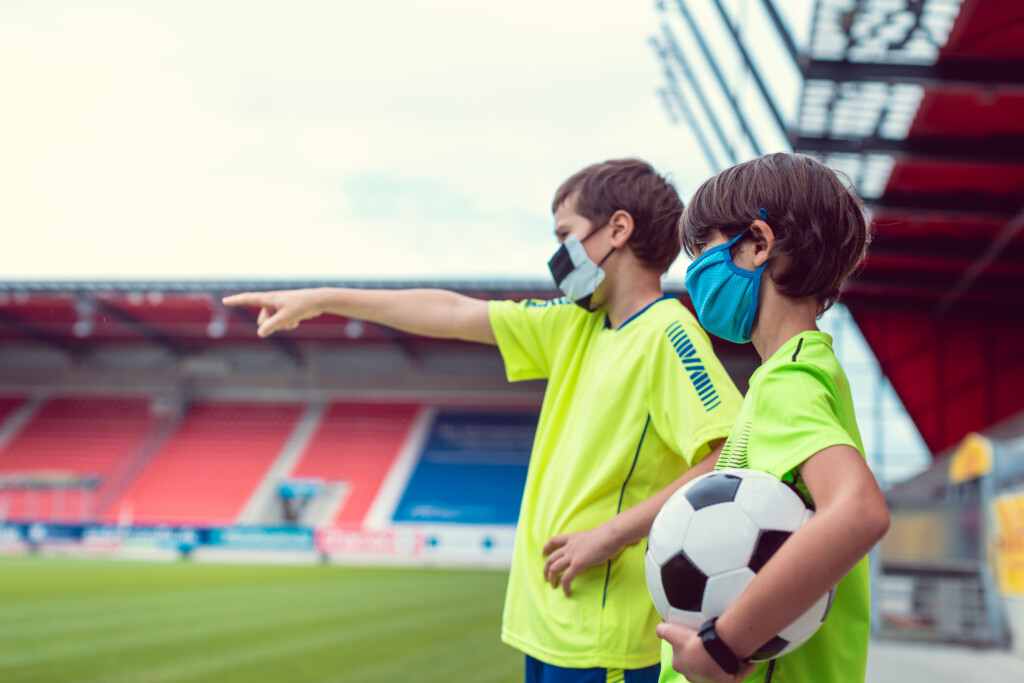 Two boys wanting to play football in stadium during covid-19 wearing face masks